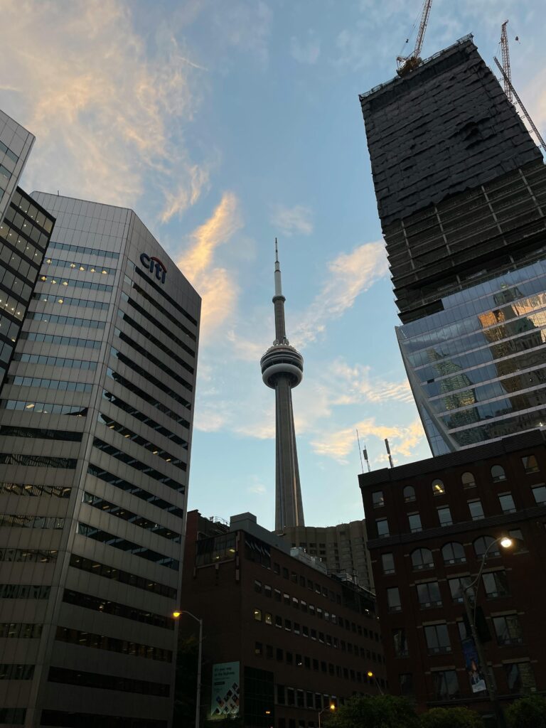 pexels-photo-14334543-14334543 View of Toronto skyline with the iconic CN Tower surrounded by modern skyscrapers at dusk.